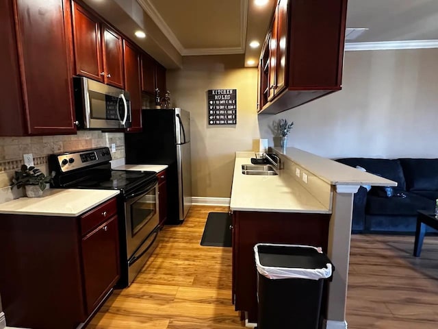 kitchen with appliances with stainless steel finishes, sink, a breakfast bar area, backsplash, and ornamental molding