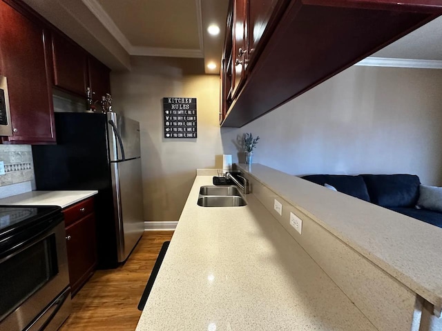 kitchen with sink, crown molding, light hardwood / wood-style flooring, appliances with stainless steel finishes, and decorative backsplash