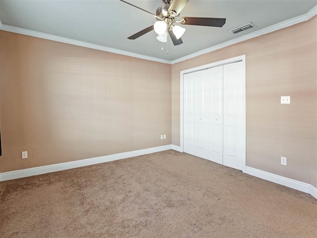 unfurnished bedroom with crown molding, carpet flooring, ceiling fan, and a closet