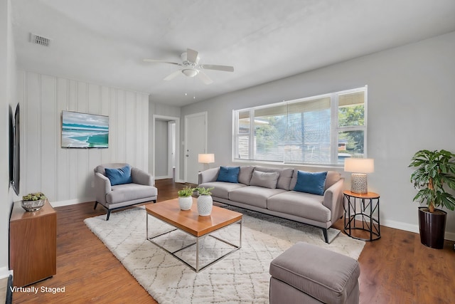 living room featuring baseboards, visible vents, ceiling fan, and wood finished floors