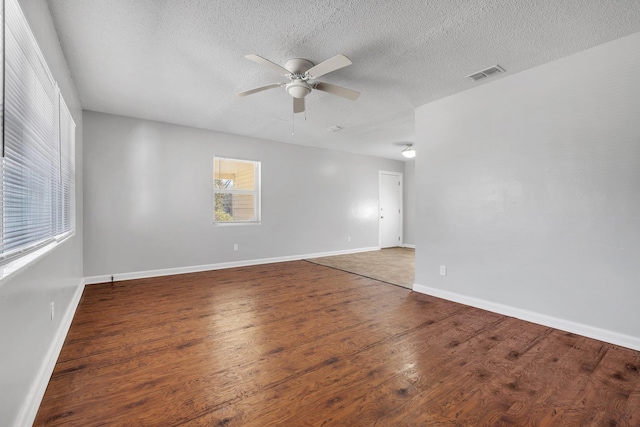 spare room featuring visible vents, a ceiling fan, a textured ceiling, wood finished floors, and baseboards