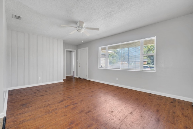 spare room featuring visible vents, a ceiling fan, a textured ceiling, wood finished floors, and baseboards