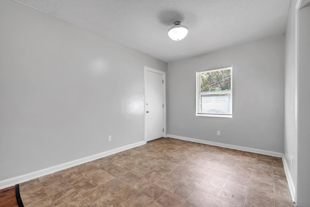 empty room with a textured ceiling and baseboards