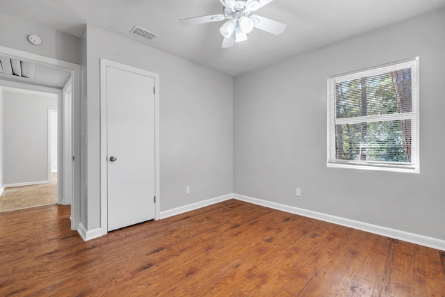 empty room with baseboards, visible vents, ceiling fan, and wood finished floors