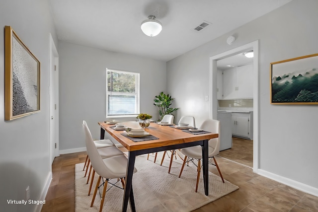 dining room featuring washer / clothes dryer, visible vents, and baseboards