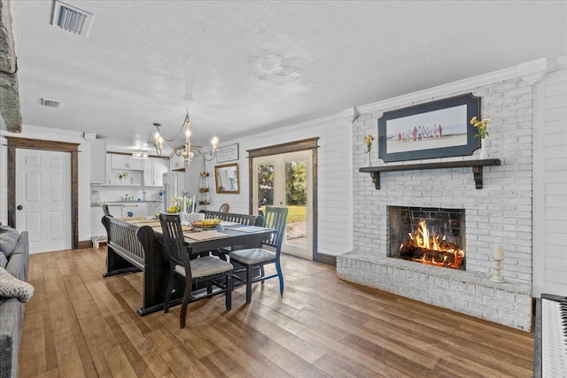 dining room with a brick fireplace, hardwood / wood-style flooring, and a textured ceiling