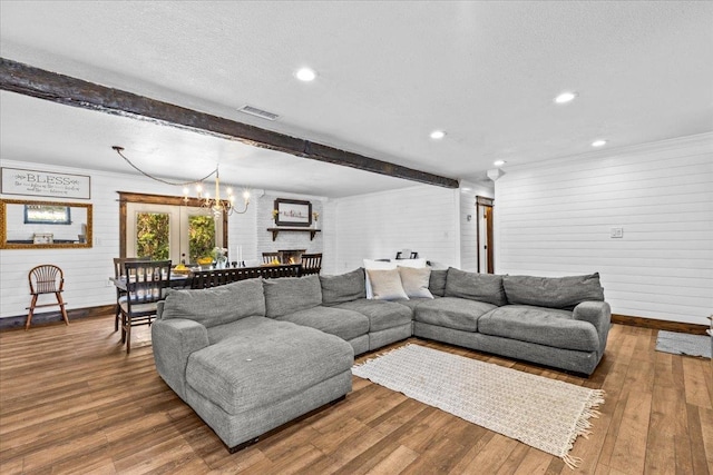 living room with hardwood / wood-style flooring, beamed ceiling, a textured ceiling, a chandelier, and french doors