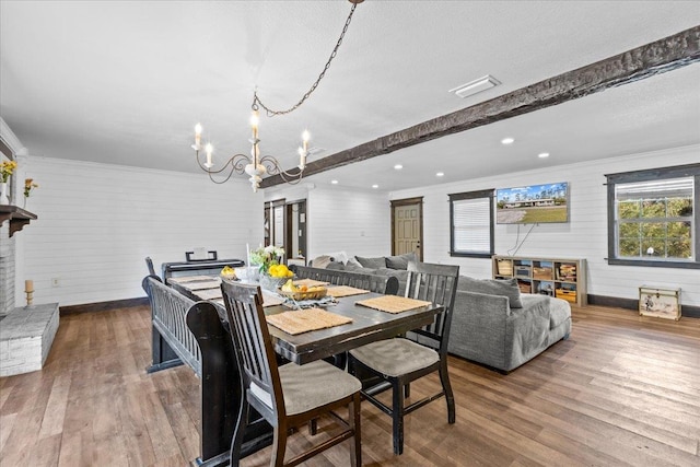 dining area featuring beamed ceiling, wood-type flooring, a chandelier, and crown molding