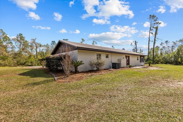 rear view of property featuring central air condition unit and a lawn