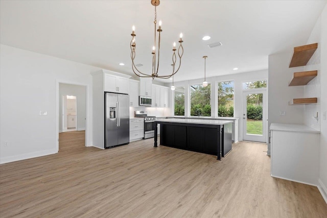 kitchen featuring stainless steel appliances, a center island, white cabinetry, light hardwood / wood-style flooring, and decorative light fixtures