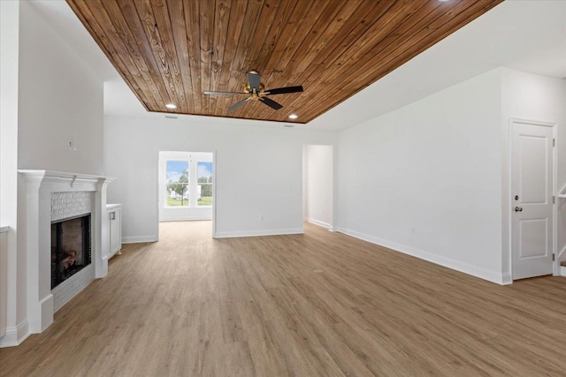 unfurnished living room featuring a brick fireplace, light hardwood / wood-style flooring, ceiling fan, and wood ceiling