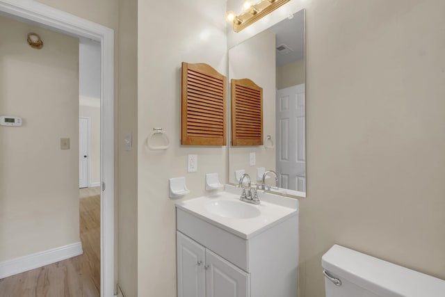 bathroom featuring wood-type flooring, vanity, and toilet