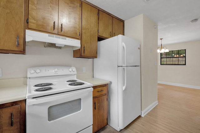 kitchen with a chandelier, pendant lighting, white appliances, and light hardwood / wood-style floors