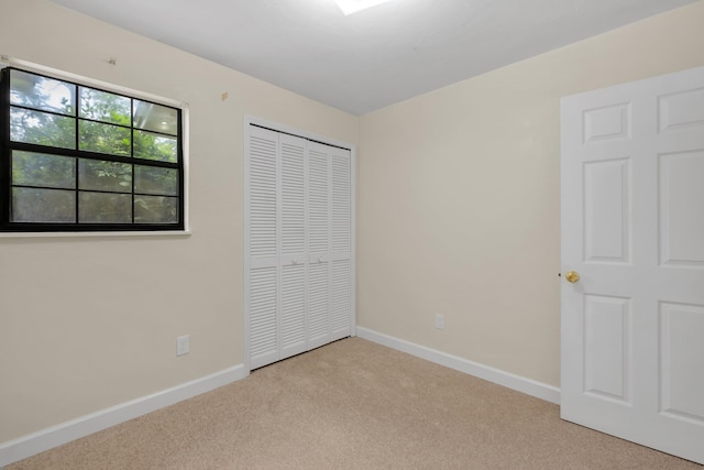 unfurnished bedroom featuring light carpet and a closet