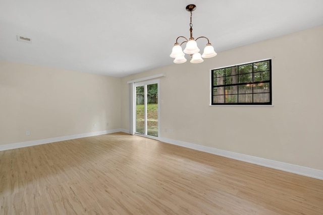 empty room featuring an inviting chandelier and light hardwood / wood-style floors