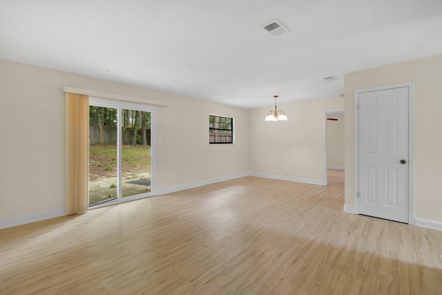 unfurnished room featuring an inviting chandelier and light wood-type flooring