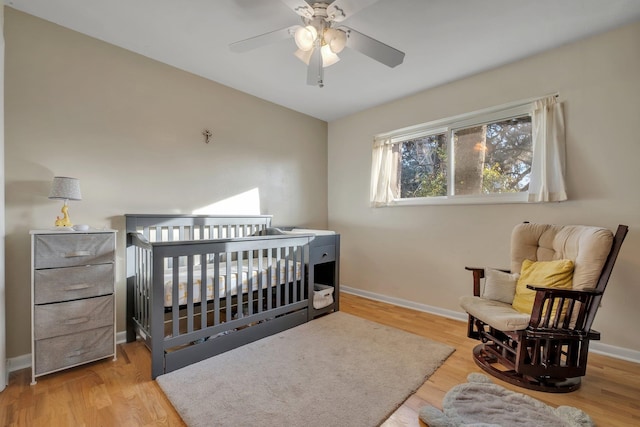 bedroom featuring ceiling fan, a nursery area, and wood-type flooring