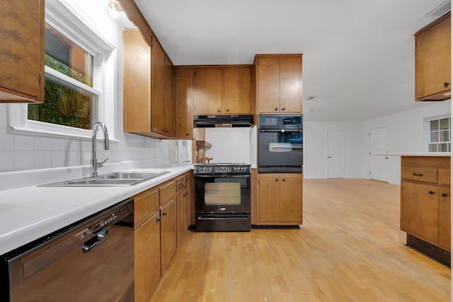 kitchen featuring black appliances, range hood, backsplash, sink, and light hardwood / wood-style flooring