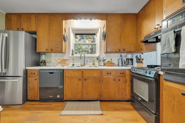 kitchen with extractor fan, sink, black appliances, and light hardwood / wood-style flooring