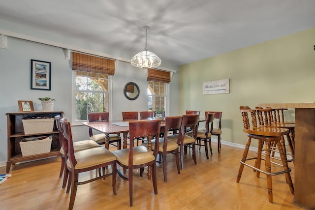 dining space with light hardwood / wood-style floors and an inviting chandelier