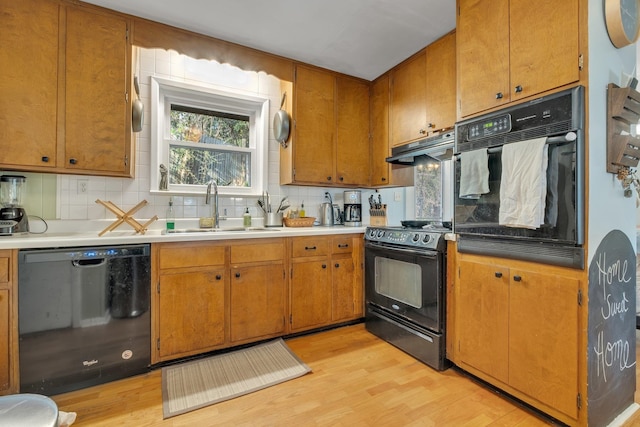 kitchen featuring light hardwood / wood-style floors, black appliances, sink, and tasteful backsplash