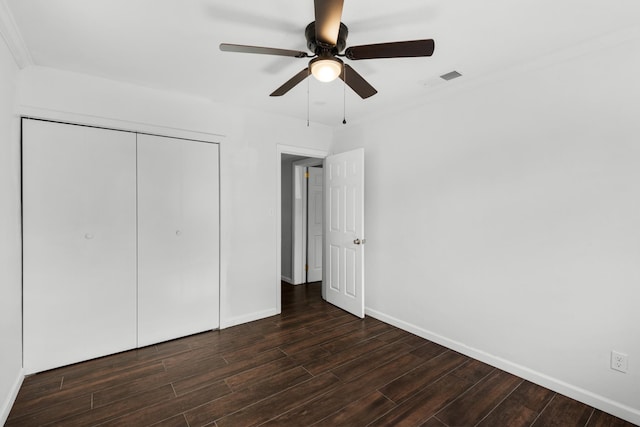 unfurnished bedroom featuring a closet, ornamental molding, dark hardwood / wood-style floors, and ceiling fan