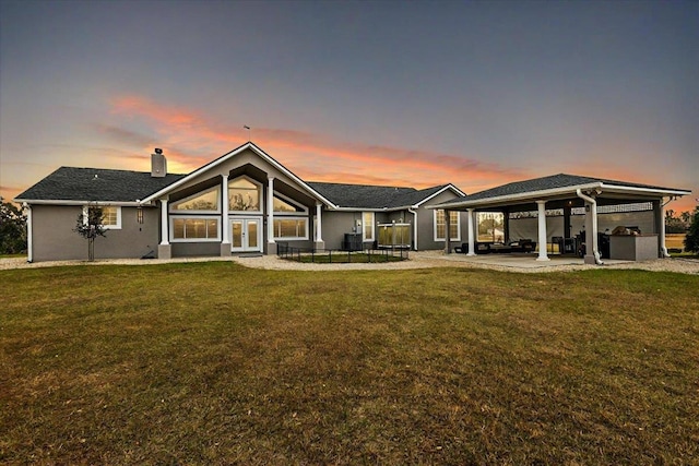 7087 Valhalla Ranch Dr, Perry, FL 32348 - back of house at dusk featuring french doors, a patio area, a chimney, and a yard
