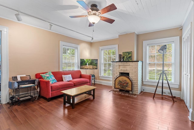 living room with a wealth of natural light, crown molding, a brick fireplace, and hardwood / wood-style floors