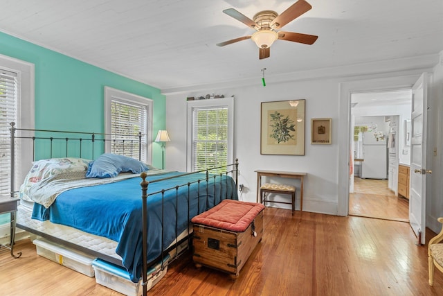 bedroom featuring freestanding refrigerator, hardwood / wood-style floors, and a ceiling fan