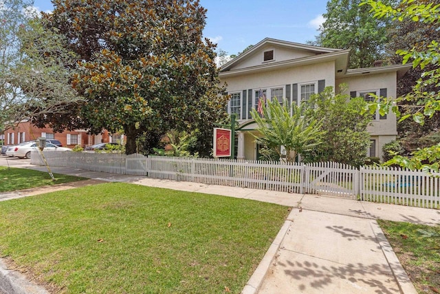 view of front of home featuring a fenced front yard, a front lawn, and stucco siding