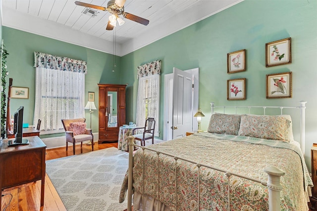 bedroom with crown molding, visible vents, ceiling fan, wood finished floors, and wooden ceiling