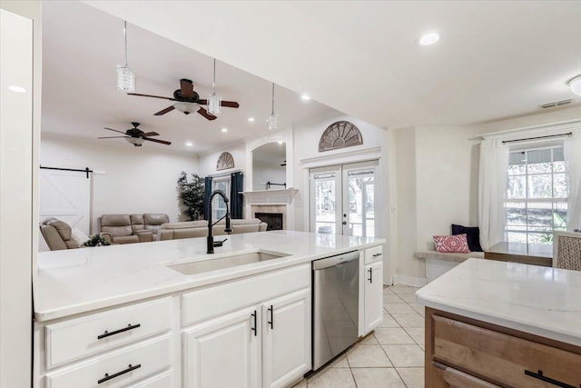 kitchen featuring light stone countertops, stainless steel dishwasher, sink, white cabinets, and light tile patterned flooring