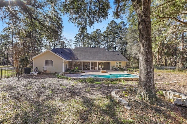 back of property with a sunroom, a patio area, and a fenced in pool