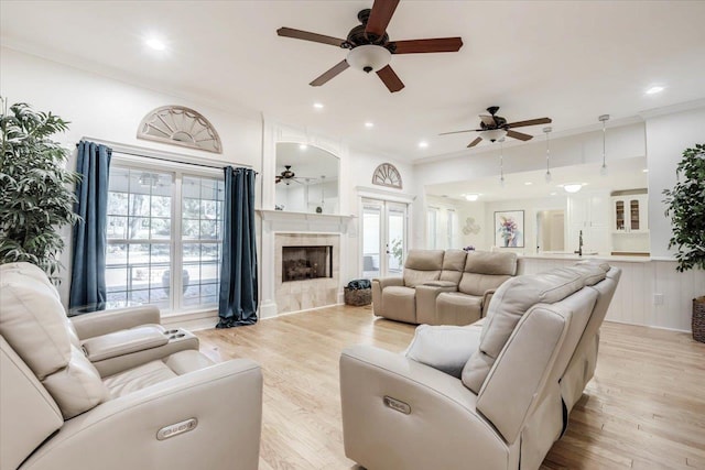 living room featuring a tiled fireplace, ornamental molding, and light hardwood / wood-style flooring