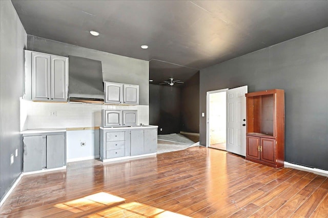 kitchen with backsplash, ceiling fan, and light wood-type flooring