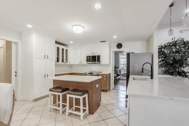 kitchen featuring stainless steel appliances, sink, white cabinets, a center island, and hanging light fixtures