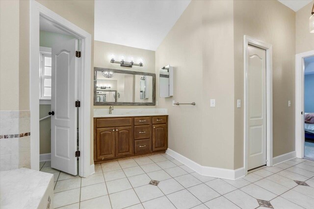 bathroom featuring tile patterned flooring, vanity, and lofted ceiling