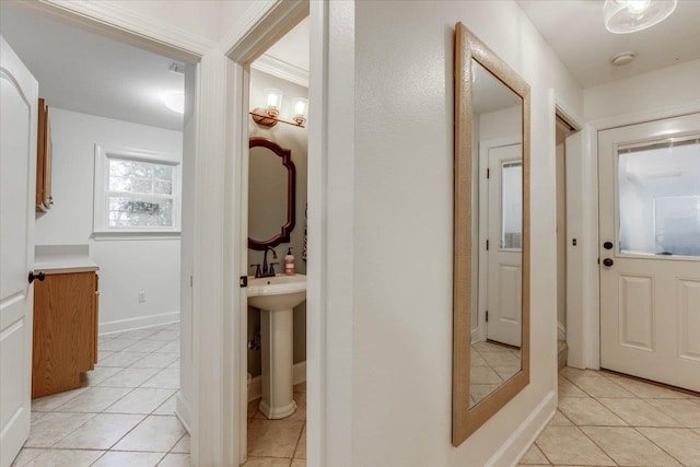 hallway featuring light tile patterned floors, crown molding, and sink