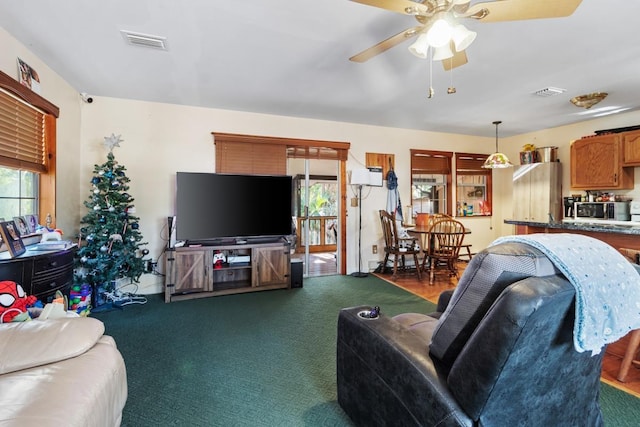 living room with dark carpet, a wealth of natural light, and ceiling fan