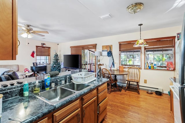 kitchen with light wood-type flooring, baseboard heating, ceiling fan, sink, and decorative light fixtures