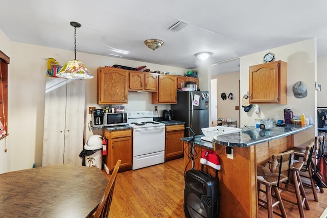 kitchen featuring pendant lighting, a breakfast bar area, light wood-type flooring, kitchen peninsula, and stainless steel appliances