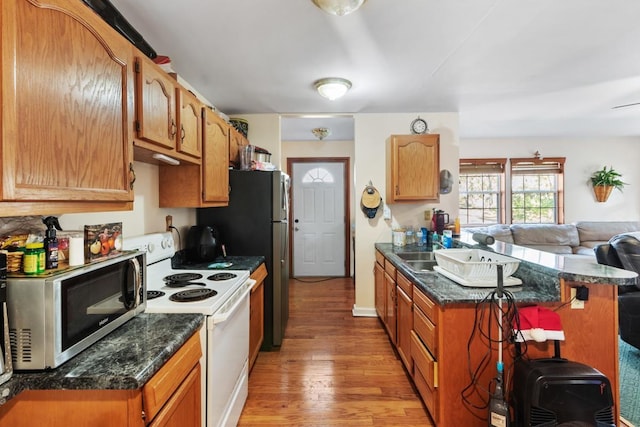 kitchen featuring a kitchen breakfast bar, sink, white electric stove, dark stone countertops, and light wood-type flooring