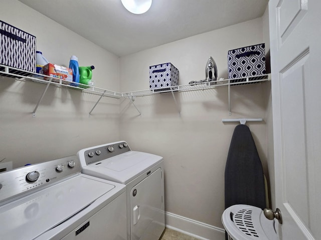 clothes washing area with baseboards, washer and dryer, and laundry area