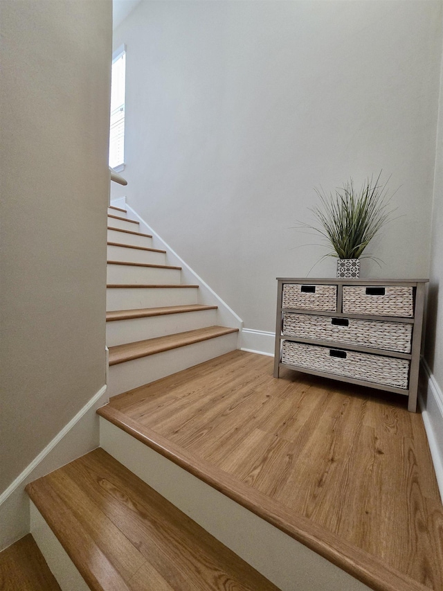 staircase featuring baseboards and wood finished floors