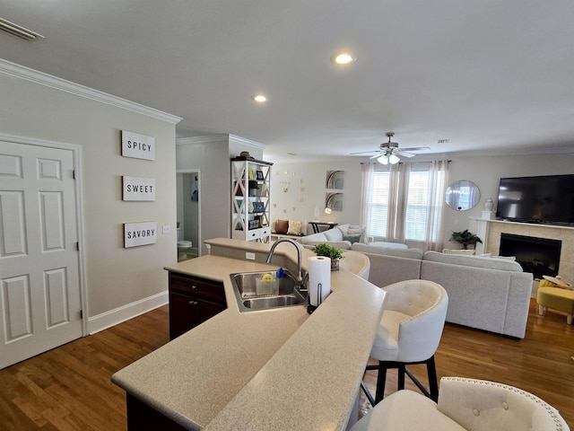 kitchen featuring a sink, a ceiling fan, a breakfast bar, visible vents, and dark wood-style flooring