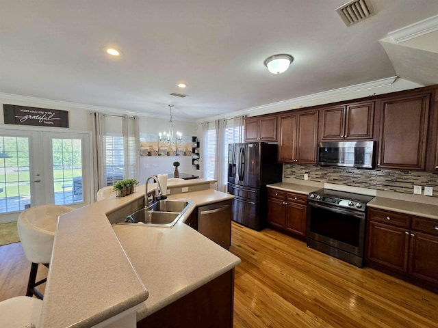 kitchen featuring an inviting chandelier, a sink, stainless steel appliances, and crown molding