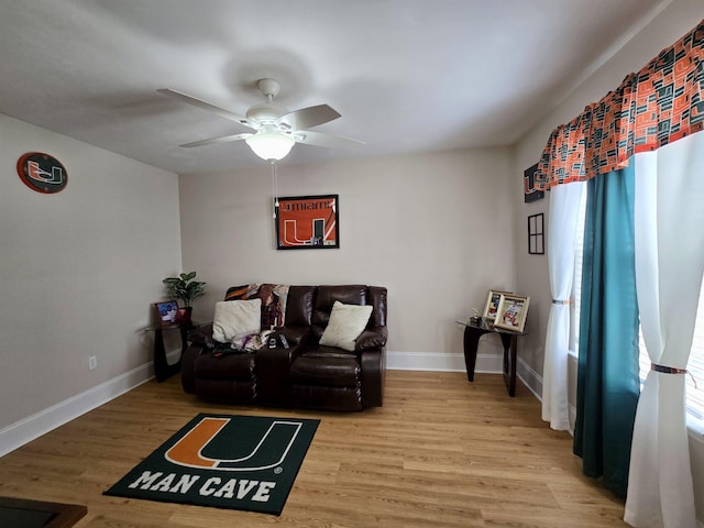 living area with baseboards, ceiling fan, and wood finished floors
