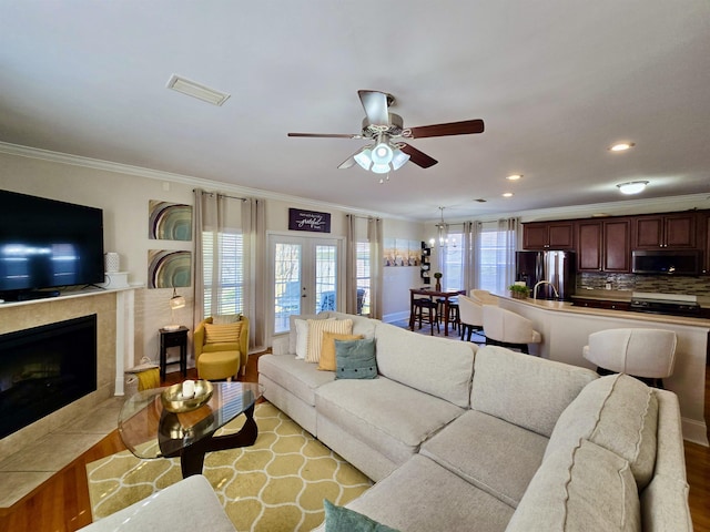 living room featuring a wealth of natural light, visible vents, and crown molding