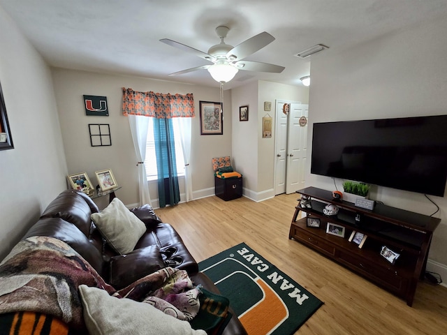 living room with baseboards, visible vents, light wood-style flooring, and a ceiling fan