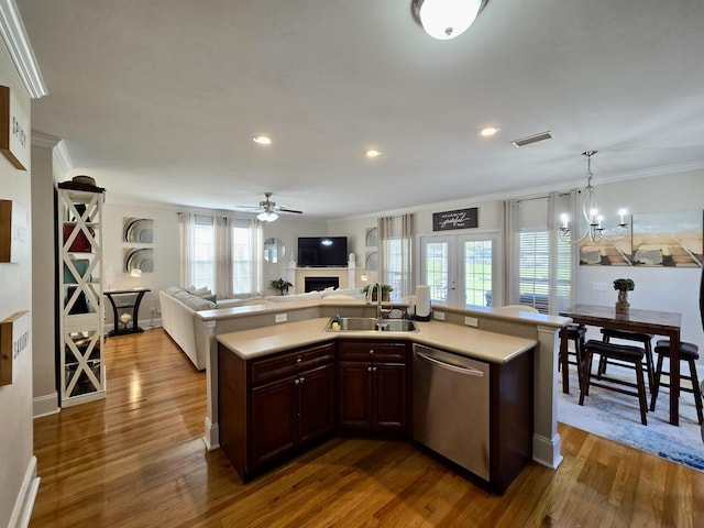 kitchen featuring dishwasher, light countertops, a sink, and a fireplace